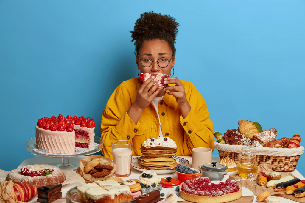 woman stress eating sugary food and desserts on the table