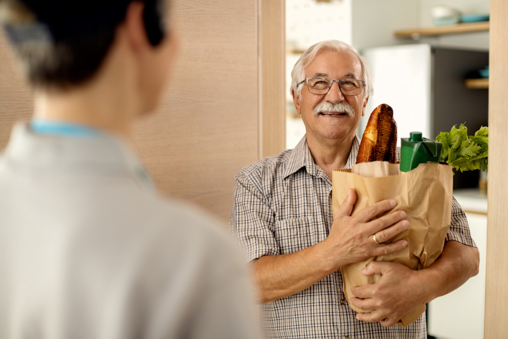 a senior man holding a grocery paper bag
